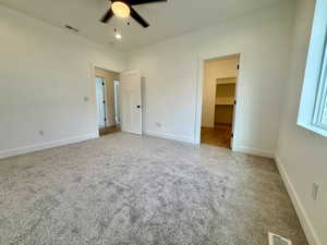 Master bedroom with light colored carpet, ensuite bathroom and a ceiling fan