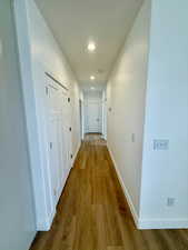 Hallway with wood finished floors and recessed lighting