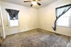 Unfurnished room featuring plenty of natural light, carpet, and ceiling fan