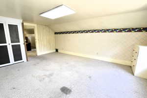 Additional living space featuring wallpapered walls, light colored carpet, and lofted ceiling