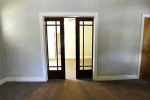 Unfurnished room with dark colored carpet and baseboards