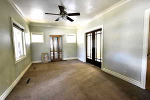 Spare room with french doors, crown molding, dark colored carpet, and a ceiling fan