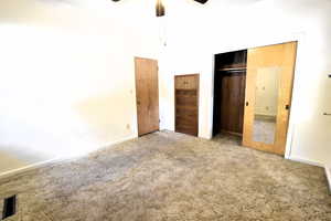 Unfurnished bedroom with carpet flooring, a closet, ceiling fan, and a high ceiling