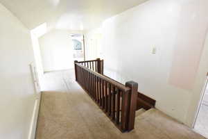 Staircase with carpet and vaulted ceiling