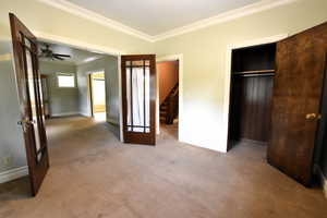 Unfurnished bedroom featuring ornamental molding, light carpet, and french doors