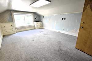 Additional living space with lofted ceiling, carpet, and wallpapered walls
