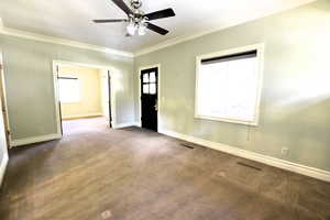 Foyer with crown molding, carpet flooring, and ceiling fan