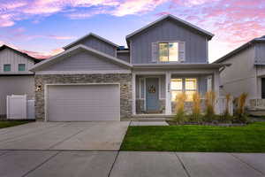 Craftsman-style home with a porch, a front lawn, driveway, board and batten siding, and a garage