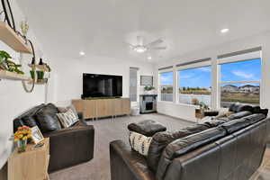 Living area featuring a fireplace, light carpet, ceiling fan, and recessed lighting