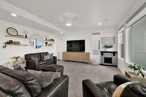 Living room with recessed lighting, a stone fireplace, carpet flooring, and a ceiling fan