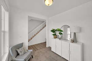 Sitting room with light colored carpet and stairs