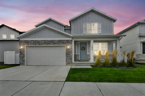 Craftsman-style house with a porch, a front yard, stone siding, concrete driveway, and board and batten siding