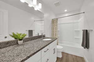 Full bath with shower / bath combo with shower curtain, vanity, and dark wood-style floors