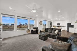 Living area with recessed lighting, light carpet, and a ceiling fan