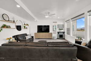 Living room with a stone fireplace, recessed lighting, carpet, and ceiling fan