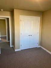 Unfurnished bedroom with dark colored carpet and a closet