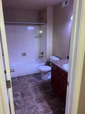 Bathroom featuring shower / bathtub combination, vanity, and stone finish flooring