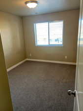 Carpeted empty room featuring a textured ceiling