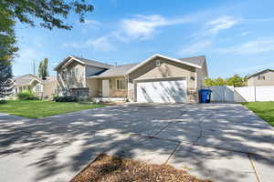 Tri-level home with a gate, concrete driveway, an attached garage, and stone siding