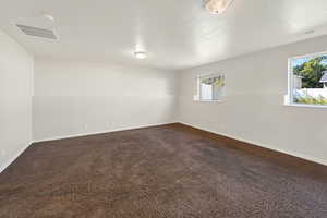 Empty room with dark colored carpet and baseboards