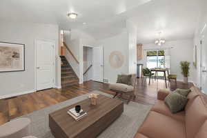 Living area featuring stairs, a chandelier, and dark wood-style floors
