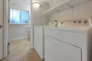 Washroom featuring washing machine and clothes dryer and light tile patterned floors