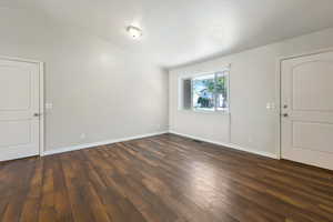 Empty room with dark wood finished floors and baseboards