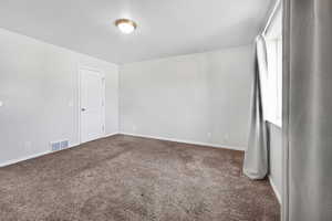 Spare room with dark colored carpet