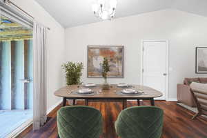 Dining area featuring dark wood-style floors, a chandelier, and vaulted ceiling