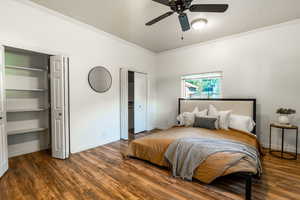 Bedroom featuring crown molding, wood finished floors, two closets, and a ceiling fan