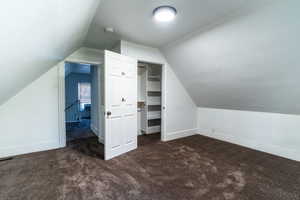 Bonus room featuring dark carpet and vaulted ceiling