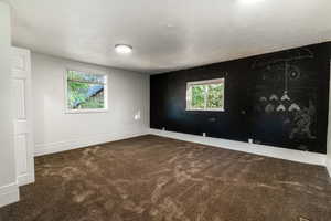 Unfurnished room with dark colored carpet and a textured ceiling