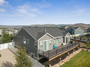 Rear view of property with a deck with mountain view, a fenced backyard, a residential view, and roof with shingles