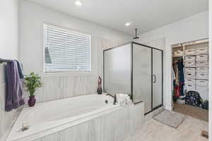 Full bathroom with a stall shower, a walk in closet, a garden tub, and recessed lighting