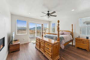 Bedroom featuring access to outside, dark wood finished floors, a textured ceiling, multiple windows, and a ceiling fan