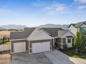 View of front facade with a shingled roof, board and batten siding, an attached garage, and driveway