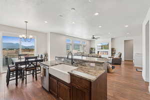 Kitchen with dark brown cabinets, dark wood-style flooring, light stone counters, a textured ceiling, and recessed lighting
