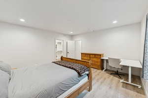 Bedroom featuring light wood finished floors, recessed lighting, a desk, and a spacious closet
