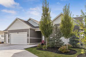 View of front facade with board and batten siding, a shingled roof, concrete driveway, and an attached garage