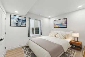 Bedroom with light wood-style floors and recessed lighting.  This has been virtually staged