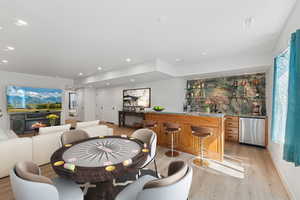 Dining room featuring light wood finished floors, bar with sink, and recessed lighting