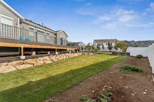 View of grassy yard featuring a wooden deck and a residential view