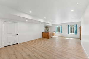 Unfurnished living room with recessed lighting, light wood-style flooring, and wet bar. This has been virtually staged