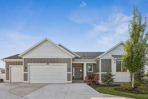 Single story home with board and batten siding, roof with shingles, concrete driveway, and a garage