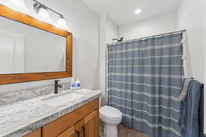 Full bath featuring vanity, curtained shower, wood finished floors, and recessed lighting