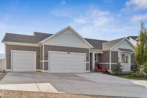 Single story home featuring board and batten siding, roof with shingles, and concrete driveway