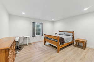 Bedroom with light wood-style flooring, recessed lighting, and an office area
