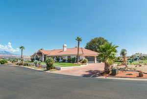 Mediterranean / spanish-style house featuring a tiled roof, driveway, a chimney, a garage, and stucco siding