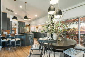 Kitchen featuring dark countertops, lofted ceiling, a breakfast bar area, light wood-type flooring, and stainless steel refrigerator