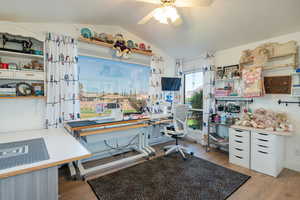 Kitchen featuring light wood finished floors, a desk, open shelves, white cabinetry, and lofted ceiling